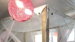 Une chambre avec un lit sous un dais, une tête de lit en bois, une couvre-lit rose et un oreiller blanc.