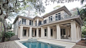 A two-story house with a swimming pool, covered patio, and a view of the surrounding trees. - 20 Oyster Catcher at The Sea Pines Resort (Hilton Head Island)