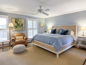 A bedroom with a bed, a chair, a lamp, a ceiling fan, and a window. - 21 Wren Drive at The Sea Pines Resort (Hilton Head Island)