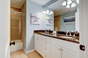 A bathroom with a double sink vanity, a shower, and artwork on the walls. - 22 Wood Ibis at The Sea Pines Resort (Hilton Head Island)