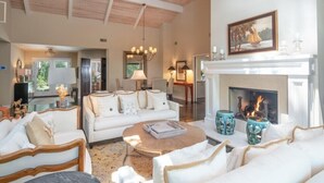 A spacious living room with a fireplace, white furniture, and a ceiling fan. - 23 Oyster Landing Road at The Sea Pines Resort (Hilton Head Island)
