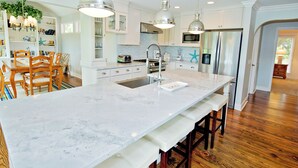 Una cocina moderna con una isla grande de mármol, iluminación colgante y sillas de madera.