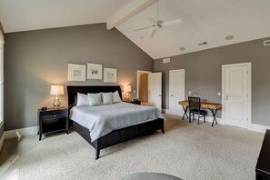 Quarto com cama, mesas de cabeceira, escrivaninha, cadeira e ventoinha no teto.