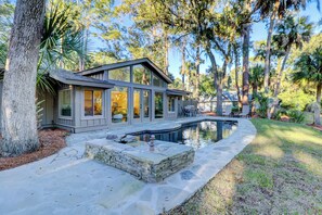 Une maison moderne dotée d’une piscine, d’une terrasse en pierre et entourée d’arbres.