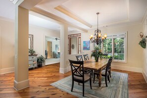 A spacious dining area with a wooden table, dark chairs, and a chandelier. - 34 Baynard Cove Rd. at The Sea Pines Resort (Hilton Head Island)