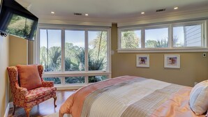 A bedroom with a large bed, a chair, and a TV mounted on the wall. - 38 Windjammer Court at The Sea Pines Resort (Hilton Head Island)