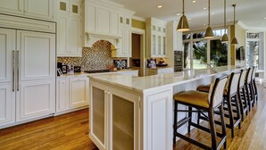 A spacious kitchen with white cabinetry, a large island with bar stools, and pendant lighting. - 38 Windjammer Court at The Sea Pines Resort (Hilton Head Island)