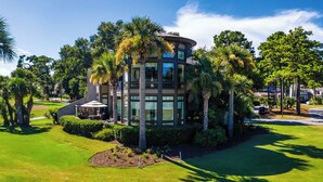 A modern building with a curved facade, surrounded by lush greenery and palm trees. - 38 Windjammer Court at The Sea Pines Resort (Hilton Head Island)