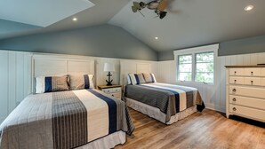Un dormitorio con dos camas, ventilador de techo, cómoda y ventana con vistas.