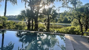 A clear view of a swimming pool with surrounding trees and a distant body of water. - 43 Stoney Creek at The Sea Pines Resort (Hilton Head Island)