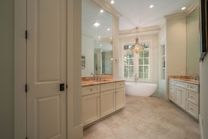 A spacious bathroom with a large vanity, a freestanding bathtub, and a large mirror.
