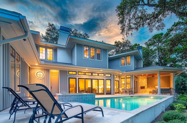 A modern house with a swimming pool, outdoor seating, and a covered patio area.