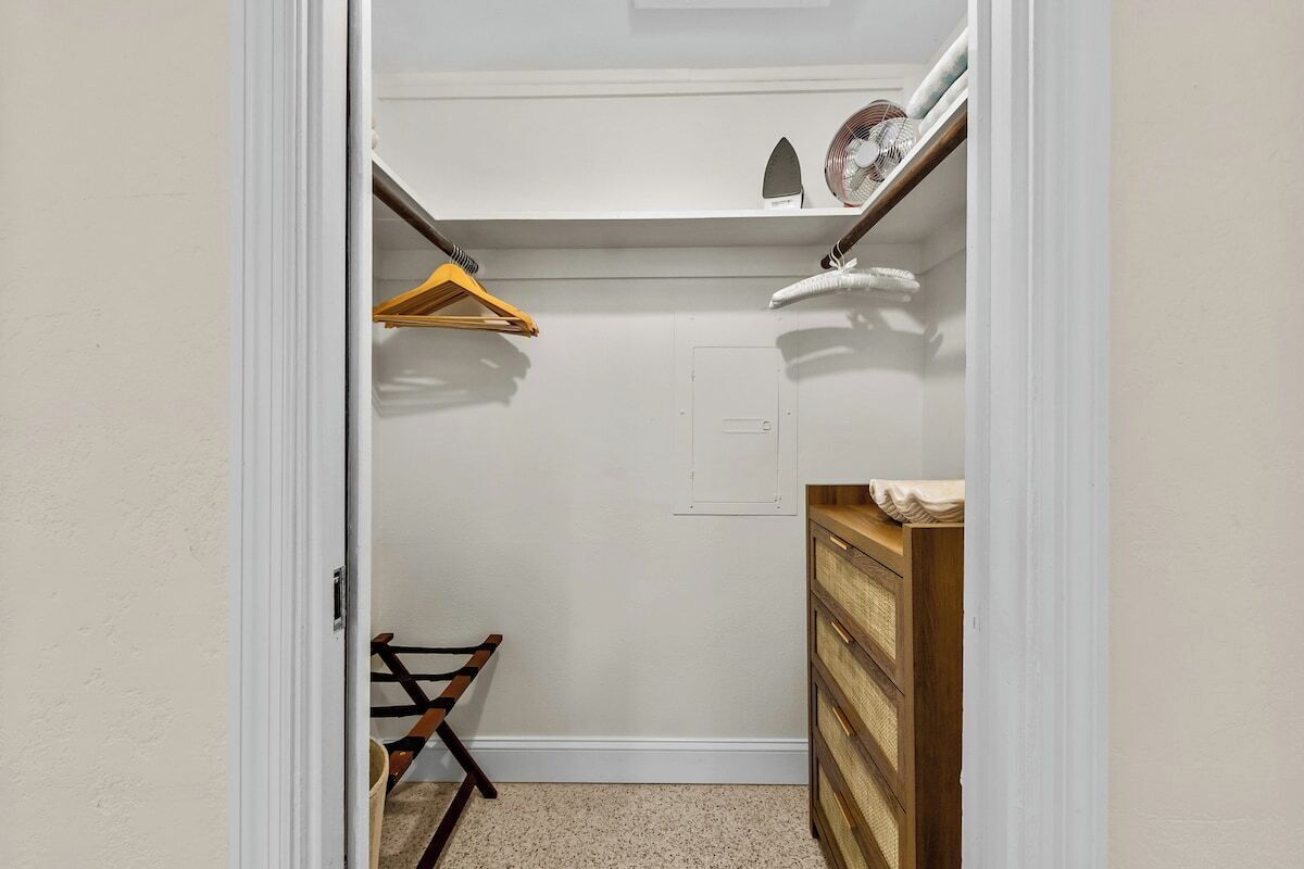 The closet contains hangers, a small dresser, a luggage rack, fan, and a laundry basket.