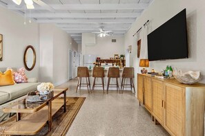 A living room with a sofa, coffee table, and a TV mounted on the wall.