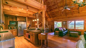 A spacious log cabin interior with a kitchen, dining area, and living room.
