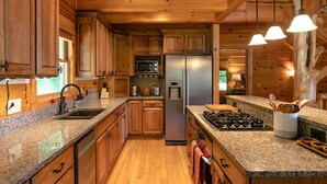 A modern kitchen with granite countertops, wooden cabinets, stainless steel appliances, and a gas stove.