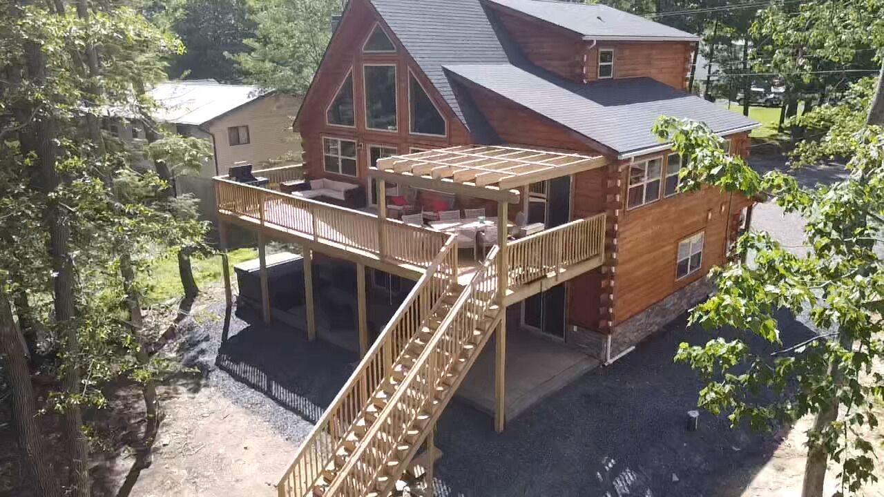 A wooden cabin with a deck and a staircase leading to a second floor.