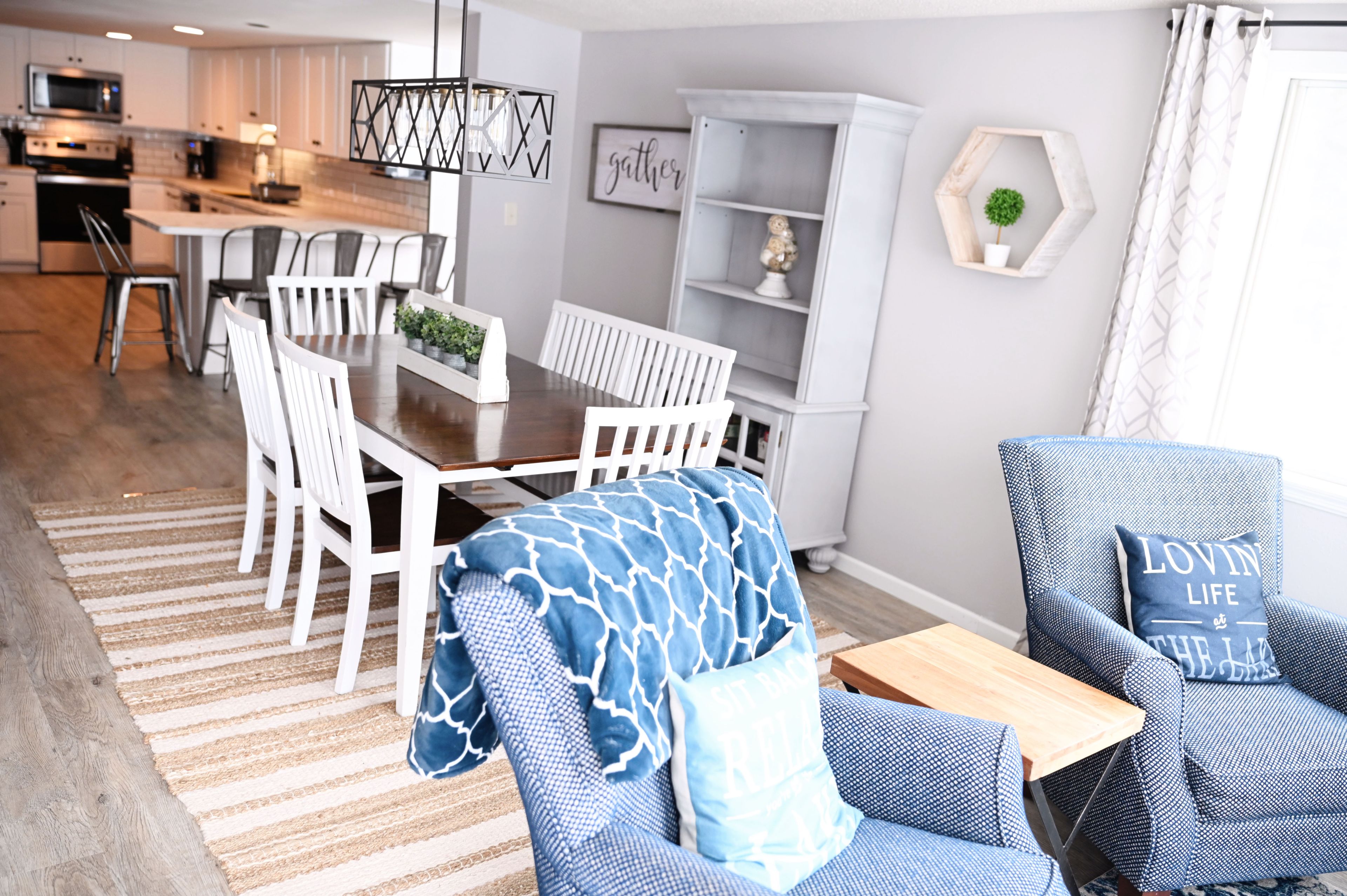 Een moderne woonkamer met een eethoek, een keuken op de achtergrond en uitzicht op het buitenleven.