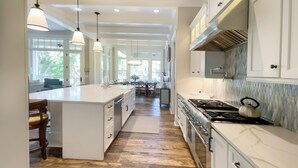 A spacious kitchen with a large island, modern appliances, and ample natural light from large windows. - 147 N. Sea Pines Dr. at The Sea Pines Resort (Hilton Head Island)