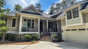 A two-story house with a front porch, a garage, and a well-maintained lawn. - 147 N. Sea Pines Dr. at The Sea Pines Resort (Hilton Head Island)
