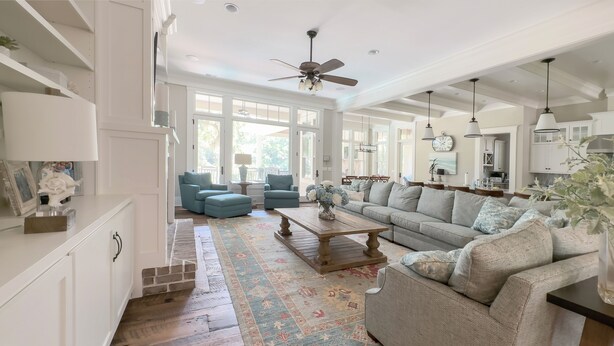 A spacious living room with a large sofa, a coffee table, and a fireplace. There are two blue armchairs and a rug on the floor. - 147 N. Sea Pines Dr. at The Sea Pines Resort (Hilton Head Island)