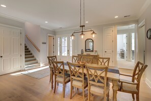 A dining area with a wooden table and chairs, a chandelier, and a staircase leading to another room. - 68 Shell Ring Rd. at The Sea Pines Resort (Hilton Head Island)