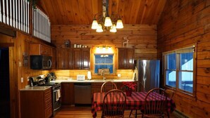 L’intérieur d’un chalet en bois comprend une cuisine, un coin repas et une grande fenêtre.