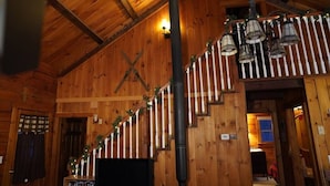 Un intérieur en bois avec un escalier, des murs en bois et un tuyau noir.