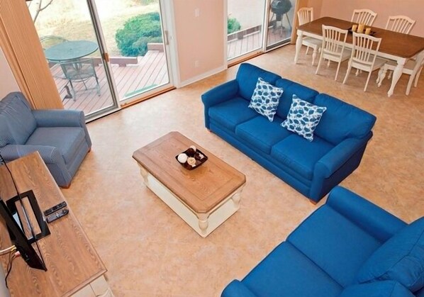 A living room with a blue sofa, a wooden coffee table, and a TV stand. - 282 Stoney Creek Villa at The Sea Pines Resort (Hilton Head Island)