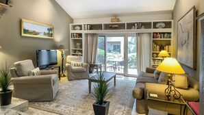A living room with a sofa, armchair, coffee table, TV, and a bookshelf.