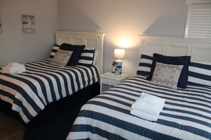 A hotel room with two beds, each with striped bedding and matching pillows. There is a nightstand with a lamp between the beds. - 241 Stoney Creek at Sea Pines Resort (Hilton Head Island)
