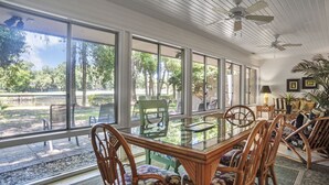 A spacious room with large windows, wicker furniture, and ceiling fans.