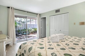 Ein Schlafzimmer mit Bett, Sessel, Schiebetür zu einem Außenbereich und Kleiderschrank.