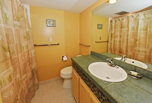Een badkamer met gele muren, een witte wastafel en een toilet.