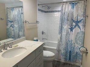 Et badeværelse med vask, toilet og bruseområde.