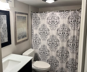 Un baño con inodoro, lavabo y cortina de ducha con estampado blanco y negro.