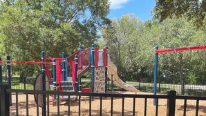 A playground with a slide, climbing structures, and a red and blue play area.