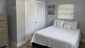A bedroom with a bed, a dresser, a closet, and a ceiling fan.