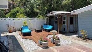 A backyard with a wooden deck, two blue sofas, and potted plants.