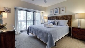 A bedroom with a large bed, a ceiling fan, a nightstand, a dresser, and a window with curtains. - 540 Plantation Club Villas at The Sea Pines Resort (Hilton Head Island)