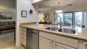 A modern kitchen with a double sink, stainless steel appliances, and a large window offering a view of the outdoors. - 540 Plantation Club Villas at The Sea Pines Resort (Hilton Head Island)