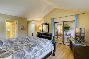 A bedroom with a bed, dresser, TV, and a sliding glass door leading to a balcony. - 552 Ocean Course at Sea Pines Resort (Hilton Head Island)