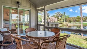 A covered patio with wicker furniture and a view of a golf course and lake. - 559 Ocean Course at The Sea Pines Resort (Hilton Head Island)