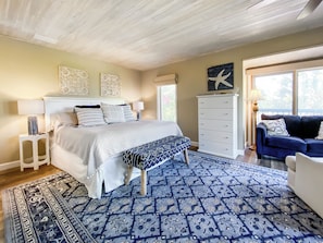 A bedroom with a bed, bedside tables, a dresser, a blue sofa, and a patterned rug.