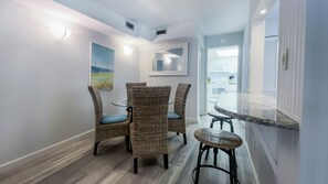 A modern kitchen with white cabinets, a marble countertop, and a dining area with wicker chairs and a glass table. - 825 Ketch Court at The Sea Pines Resort (Hilton Head Island)