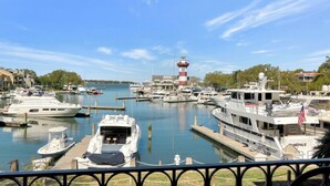 Un puerto deportivo con varias embarcaciones amarradas, un faro destacado y vistas del entorno, incluyendo edificios y árboles.