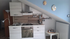 A modern kitchen with a central island, built-in oven, and gas stove. There is a small table and a radiator on the wall.