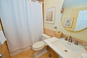 Un baño con inodoro, lavamanos y cortina de ducha.