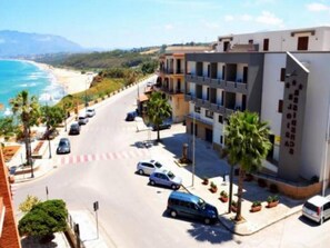 A coastal hotel with a view of the beach, multiple parking spaces, and a pedestrian pathway. - Residence Eloisa (Balestrate)