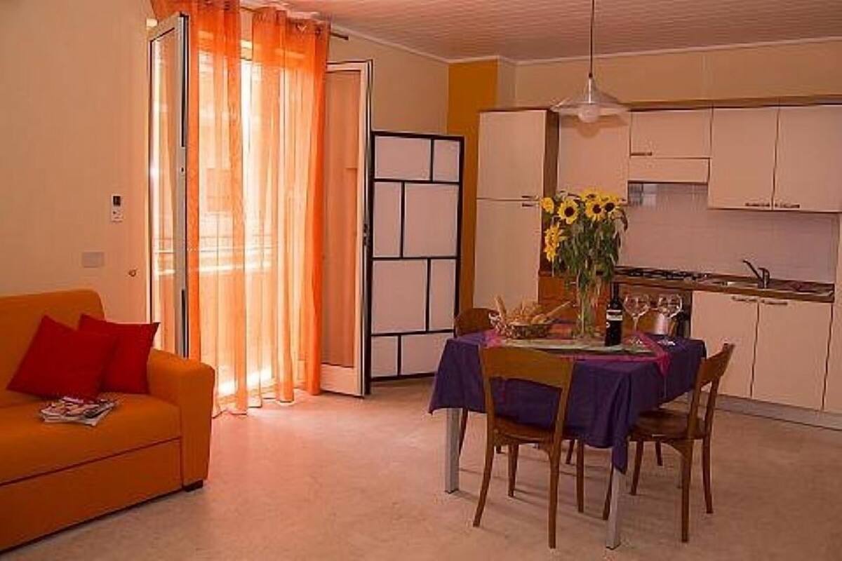 A compact living space with a dining area, a kitchenette, and a sofa with red cushions.